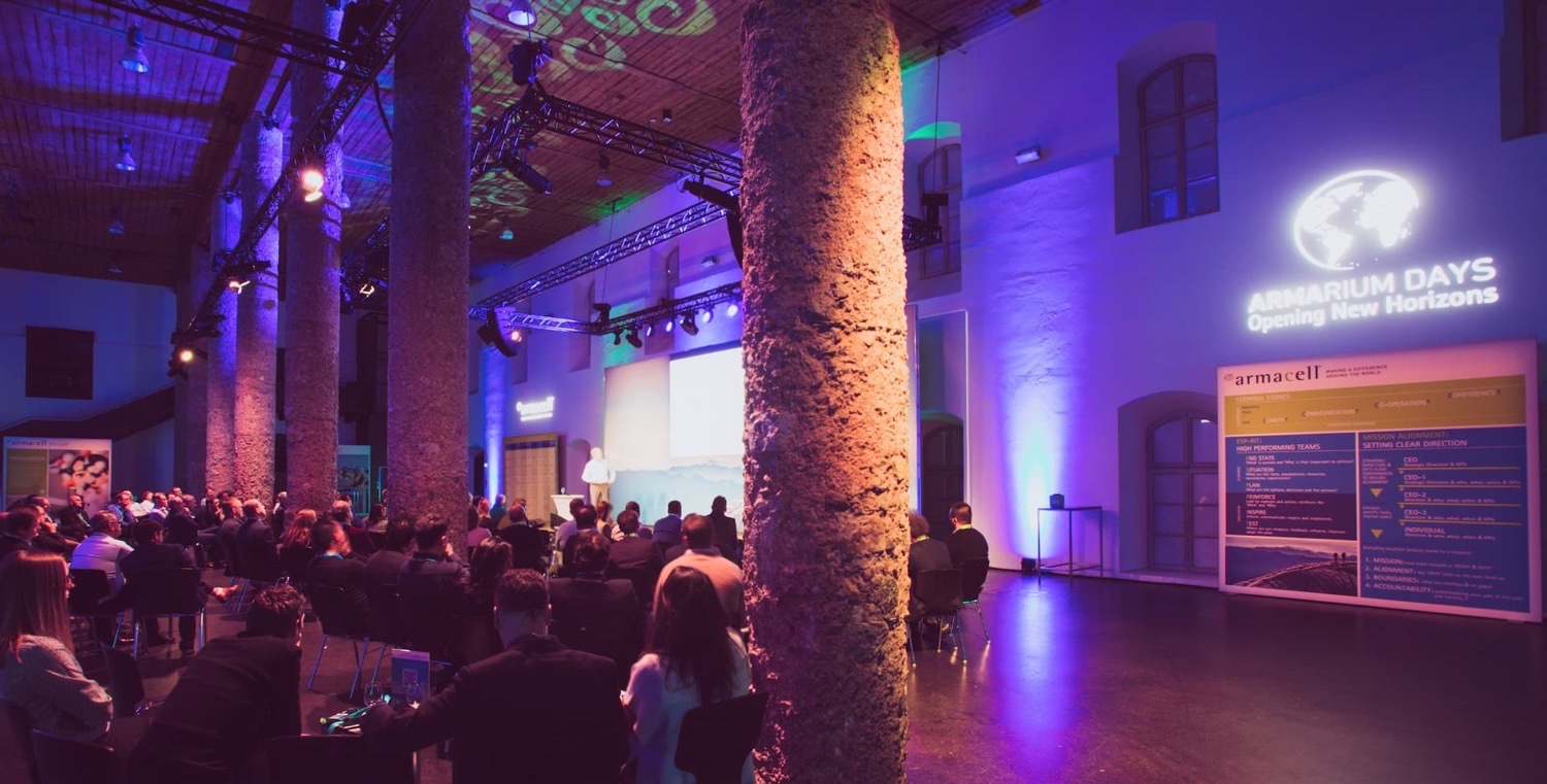The Armacell Armarium Days hall serves as a public area with a view of the stage, screen and professional corporate event setup.