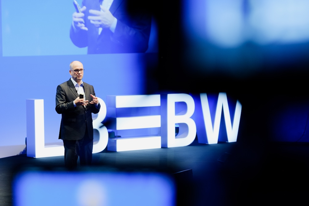 Redner auf der Bühne der LBBW Führungskräfte-Konferenz mit LBBW Logo im Hintergrund