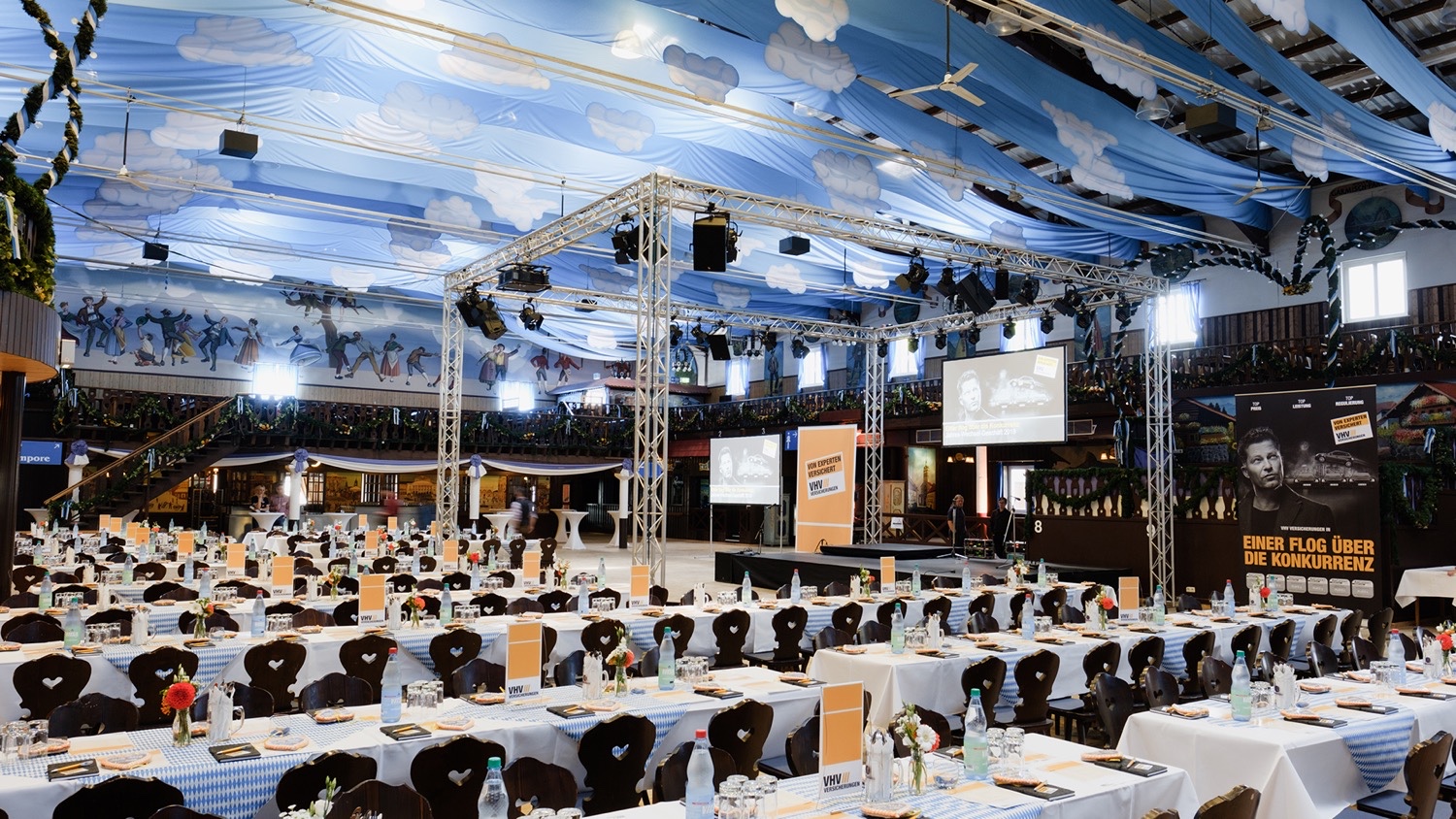 Gedeckter Oktoberfest-Saal mit Bühne für das VHV Salesevent in Bierzeltatmosphäre