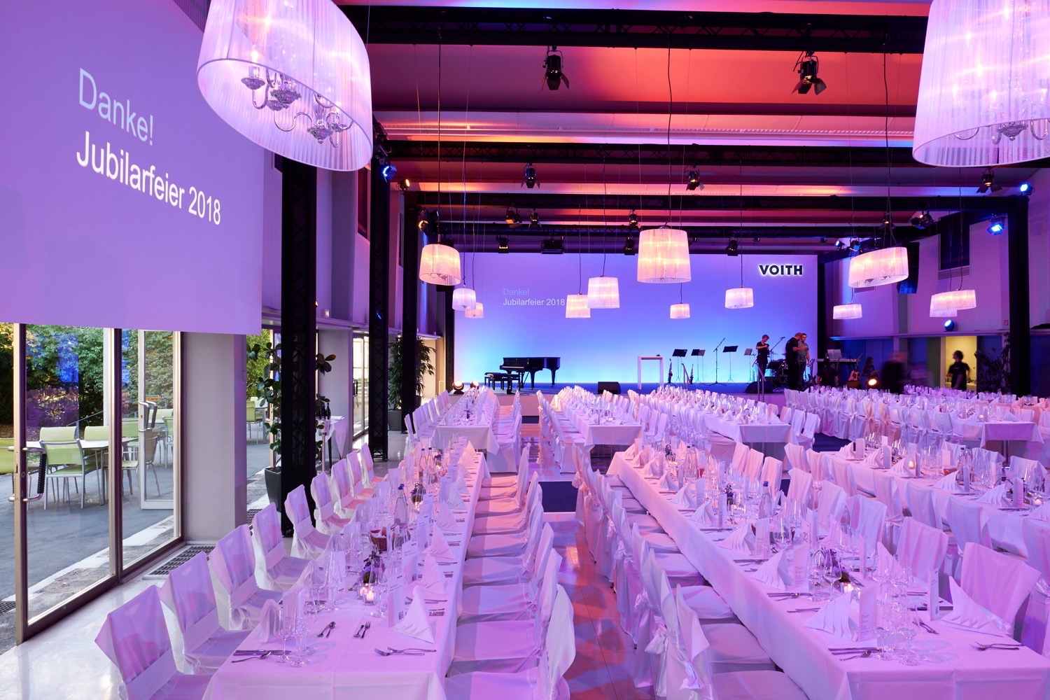 Voith Jubilarfeier im Saal mit Bühne und gedeckten Tischen Eventsaal der Voith Jubilarfeier mit Bühne, Lichtinszenierung und gedeckten Tischen